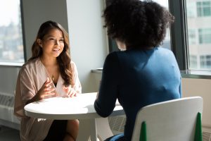 Woman talking to another woman a table